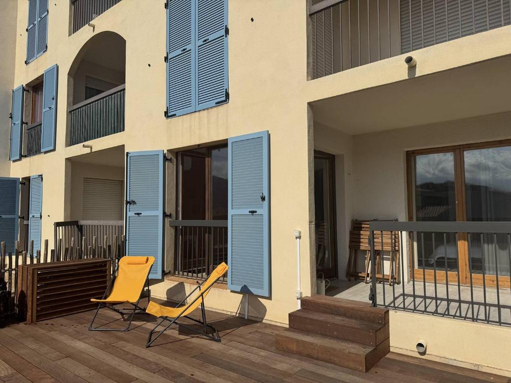 two chairs on a deck next to a building at Armonia - Appartement en centre-ville in Calvi