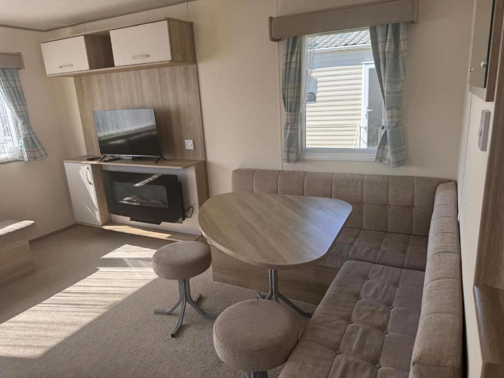 a living room with a couch and a table and a tv at Great Caravan At Dovercourt Holiday Park, Essex Ref 44206V in Great Oakley
