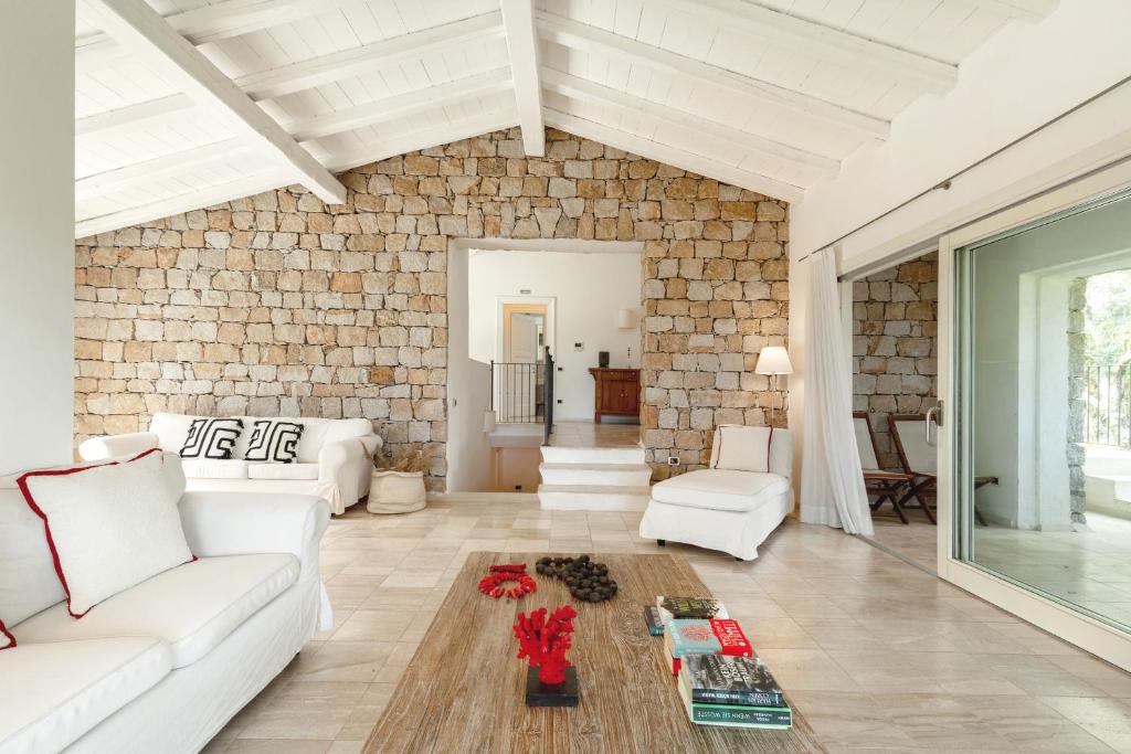 Il comprend un salon doté d'un mobilier blanc et d'un mur en briques. dans l'établissement Villa Gelsomino a soli 500 mt dal mare con piscina privata e vista mare, à Castiadas
