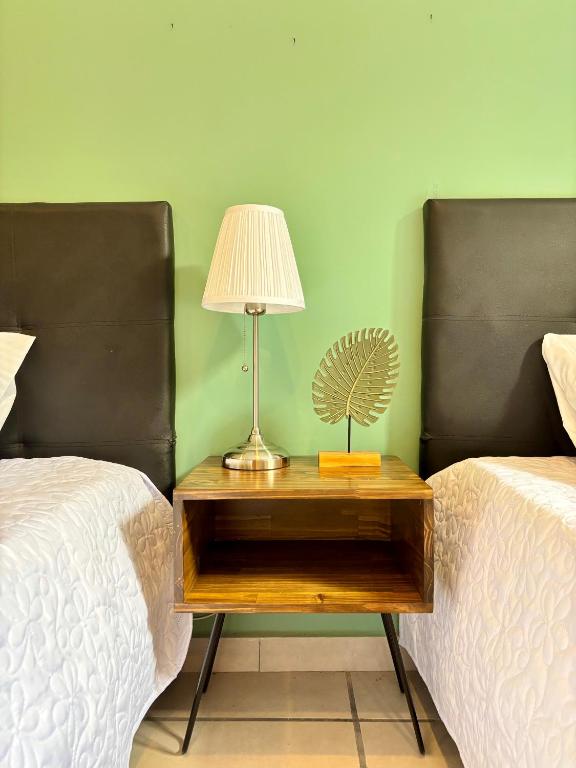 a table with a lamp on it next to two beds at TURULEKA Hostel in Roldanillo