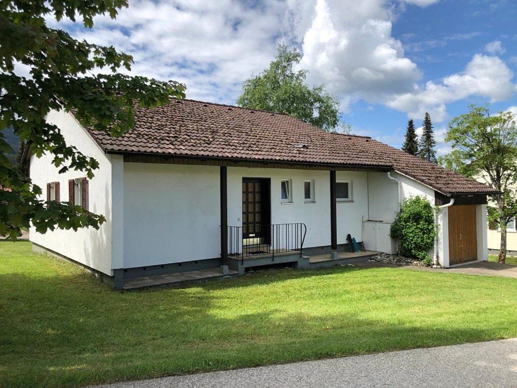 a small white house with a grass yard at Ferienhaus Fuchsweg im Feriendorf Reichenbach F17 in Nesselwang