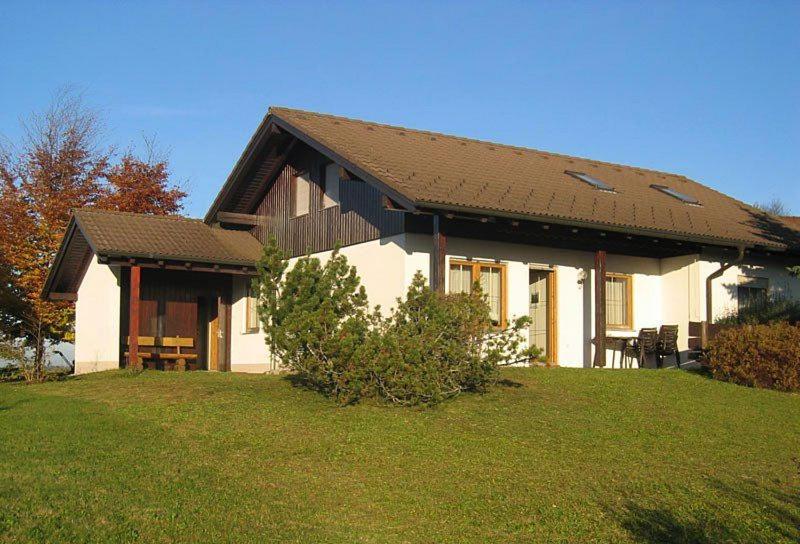 a white house with a brown roof on a yard at Ferienhaus Fuchsweg im Feriendorf Reichenbach F29 in Nesselwang