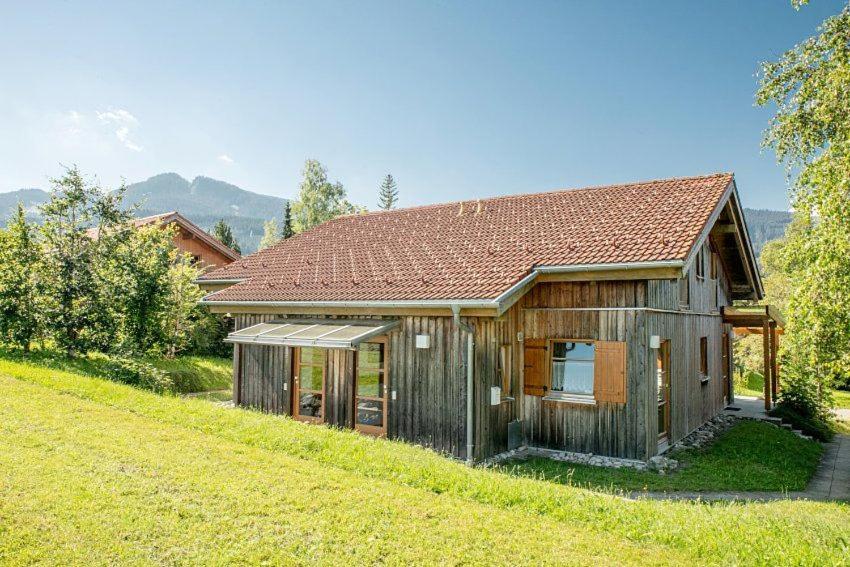 a small wooden house on a grassy hill at Ferienhaus Fuchsweg im Feriendorf Reichenbach F24a in Nesselwang
