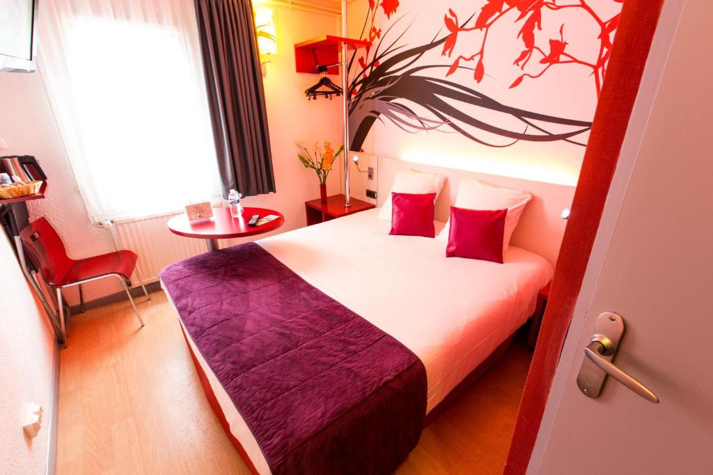 Pokój hotelowy z łóżkiem z czerwonymi poduszkami w obiekcie Hotel Inn Design Sedan w mieście Sedan