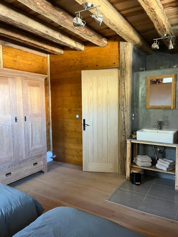 Cette chambre comprend une salle de bains pourvue d'un lavabo et d'une porte. dans l'établissement Gite les 4 Saisons - chambre Eté, à Ombre
