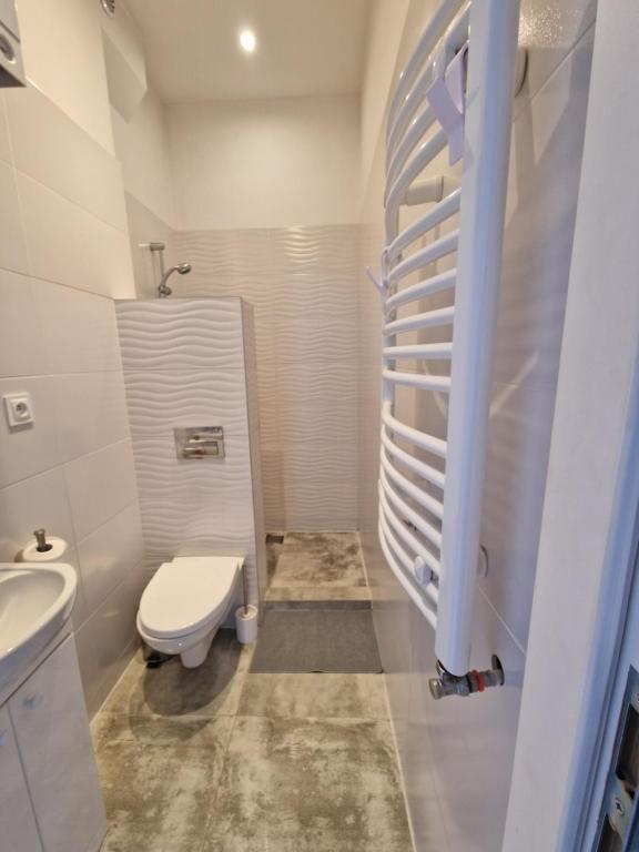 a white bathroom with a toilet and a sink at Apartamenty Zakonne "Apartament Rycerza" in Malbork