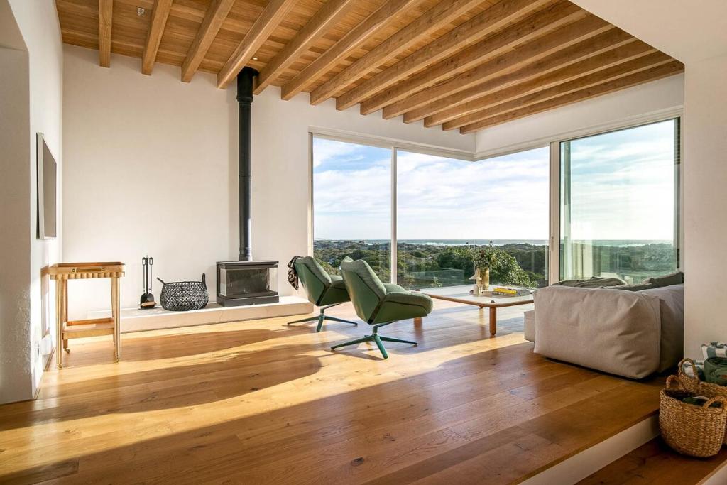 a living room with a fireplace and green chairs at Noordhoek Sunset Villa in Flat Acres