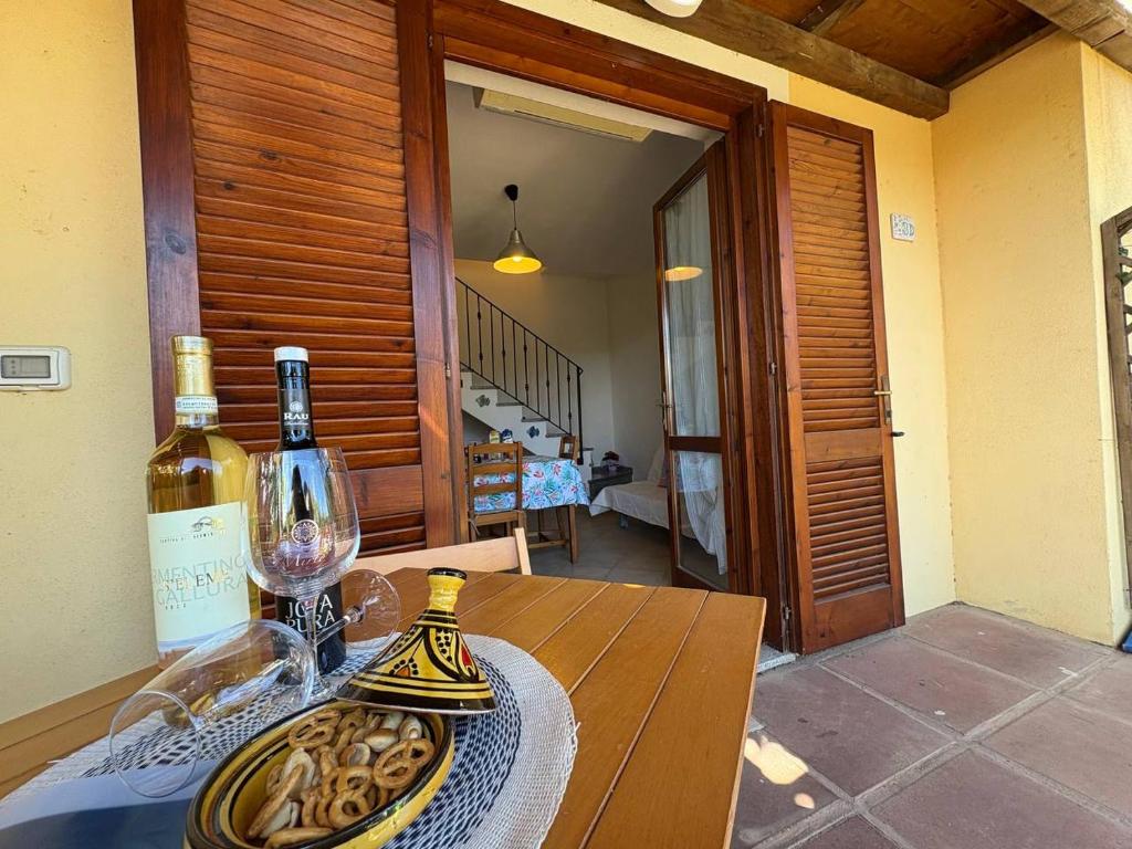 a table with a bottle of wine and a glass at AffittaSardegna - Casa Girasole in La Ciaccia