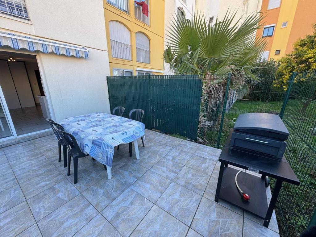- un barbecue, une table et des chaises sur la terrasse dans l'établissement Appartement T2 avec Parking et Animaux admis, Capacité 4, Cap d'Agde - FR-1-749-83, au Cap d'Agde