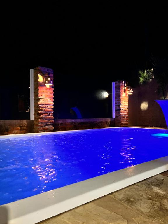 een blauw zwembad 's nachts met een gebouw bij Chalé Magia in Luis Correia