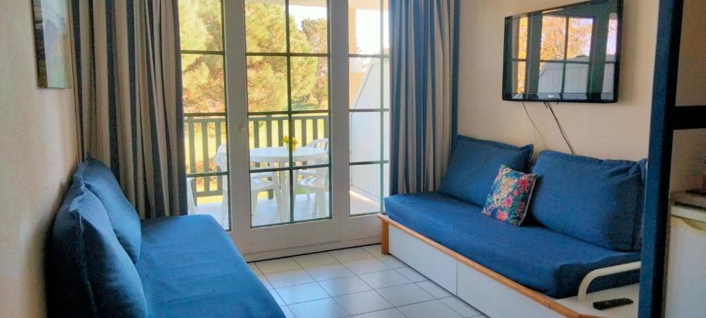 un salon avec deux canapés bleus et un balcon dans l'établissement résidence port bourgenay studio 5 personnes, à Talmont-Saint-Hilaire