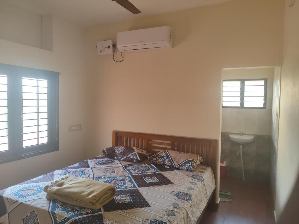 a bedroom with a bed and a sink and windows at Thiru Somasundaram in Tiruvannāmalai