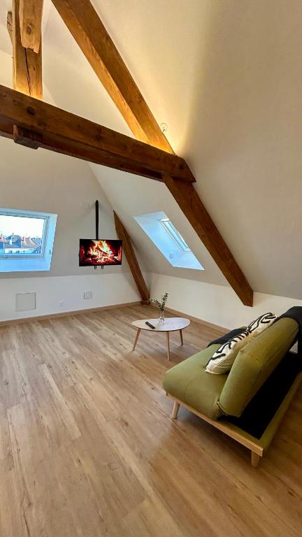 - un salon mansardé avec un canapé et une télévision dans l'établissement Appartement Moderne et Spacieux, à 10 min de la Gare, à Colmar