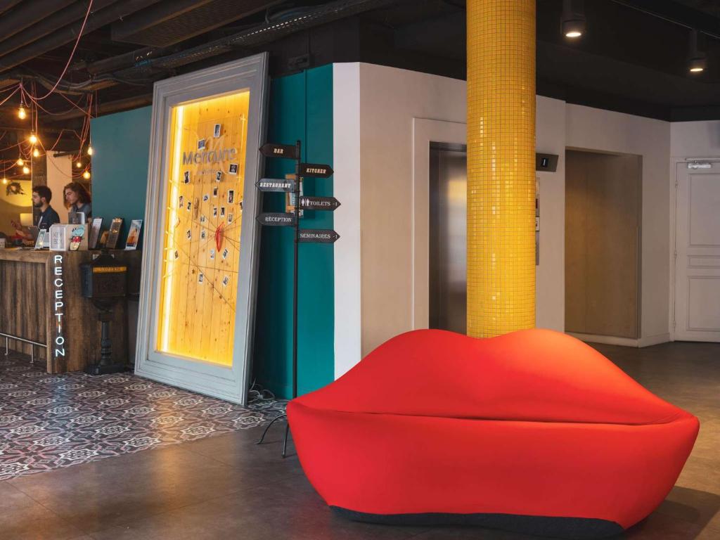 une chaise rouge dans une pièce avec une horloge sur un mur dans l'établissement Hôtel Mercure Paris Centre Gare Montparnasse, à Paris