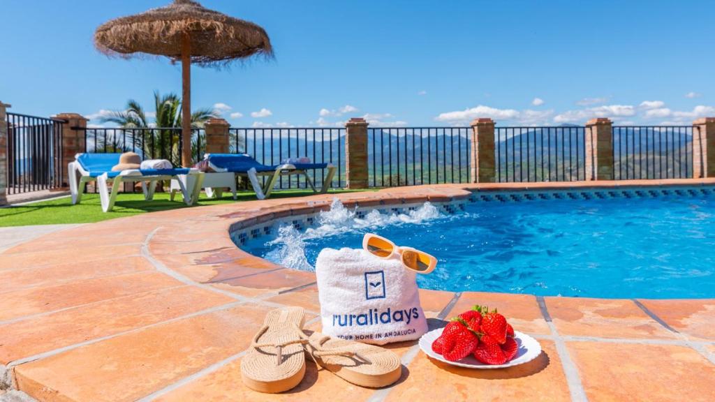 a pair of shoes and a bag of strawberries next to a swimming pool at Casa Berrocal Álora by Ruralidays in Alora