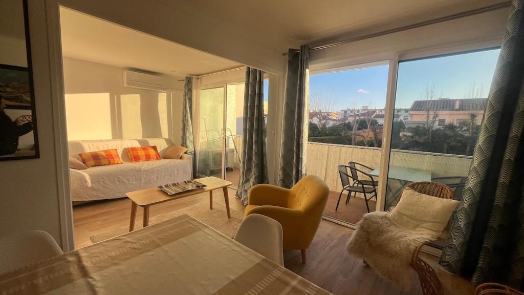 d'un salon avec un canapé et une vue sur un balcon. dans l'établissement Le Candie T3 Bord de Mer Piscine et Parking, à Canet