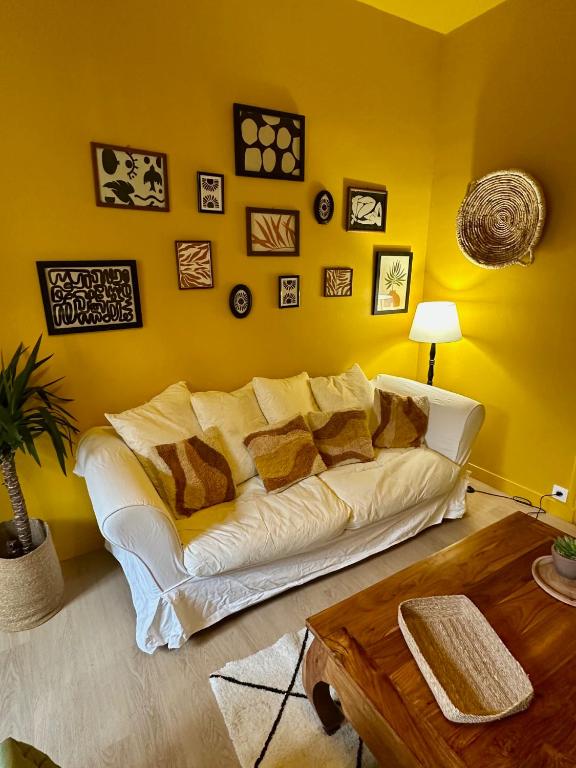 un salon avec un canapé blanc dans un mur jaune dans l'établissement Le Sunlight, Gare Centre ville, 4 Personnes, au Mans
