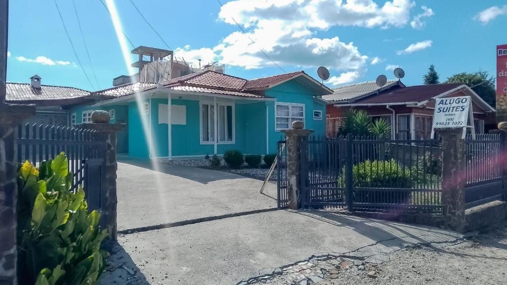a blue house with a gate with a for sale sign at Pousada e Hospedaria Alternativa Ladi Laura in Urubici