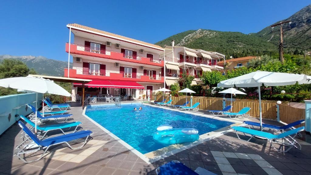 a hotel with a swimming pool with chairs and umbrellas at Sunrise studios Lefkada in Nydri