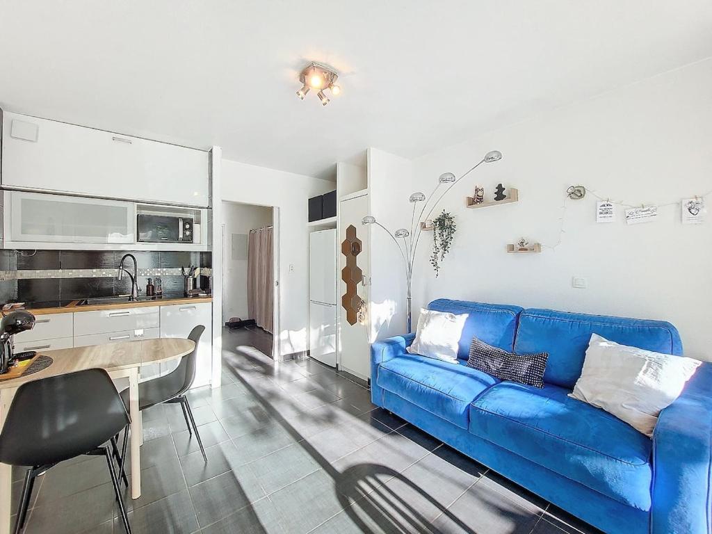 un salon avec un canapé bleu et une cuisine dans l'établissement Charmant studio Terrasse Piscine, à Sanary-sur-Mer