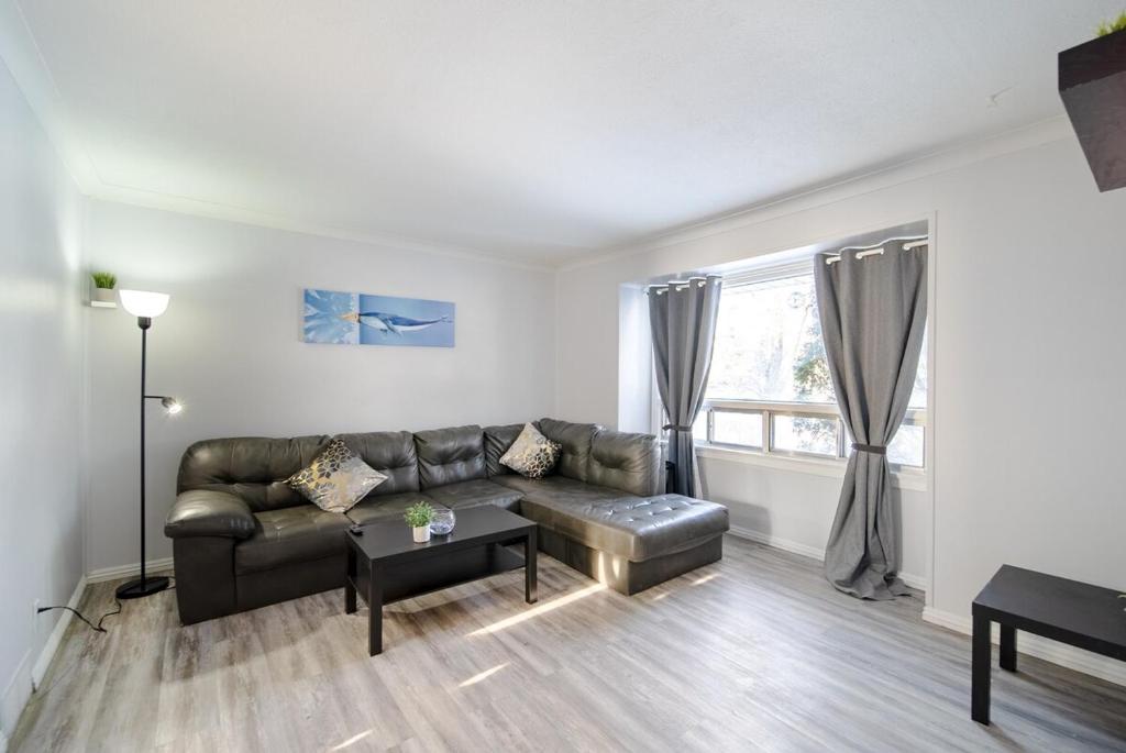 a living room with a leather couch and a table at 2 Bedroom Home In A Prime Location in Winnipeg