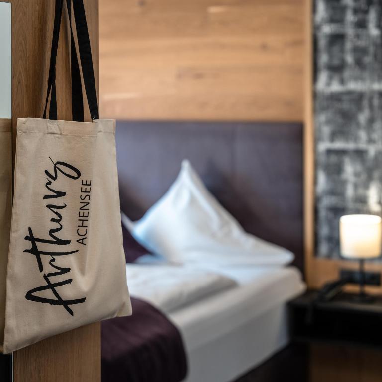 a bag hanging in a hotel room with a bed at Arthur's Hotel und Apartments am Achensee in Maurach