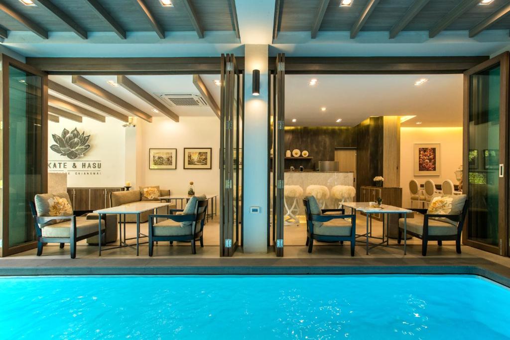 a pool in front of a dining room with a table and chairs at Kate and Hasu Boutique Chiangmai in Chiang Mai
