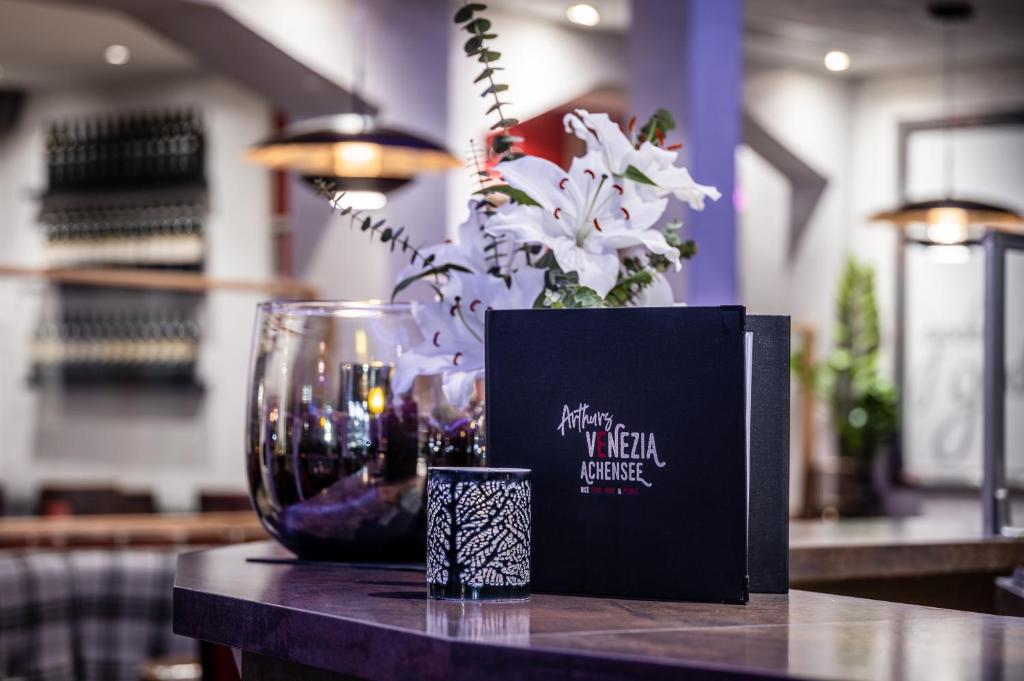 a table with a vase of flowers and a black box at Arthur's Hotel und Apartments am Achensee in Maurach