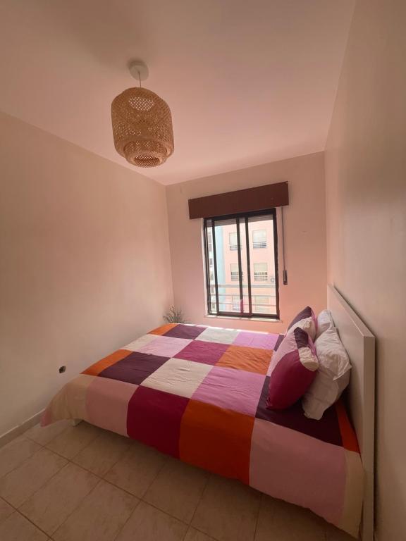 a bedroom with a colorful bed with a window at Home Away from Home in Setúbal