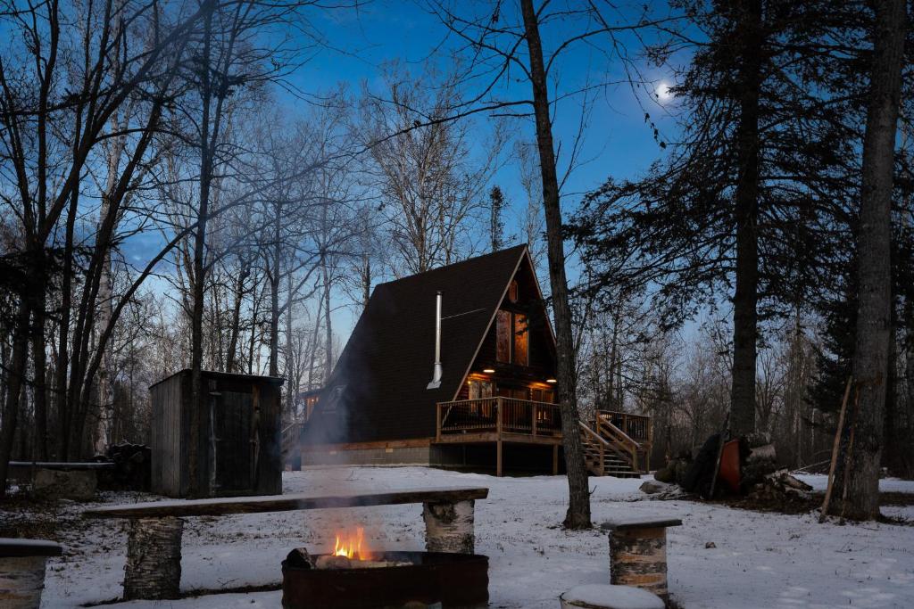 a cabin in the woods with a fire in front of it at River End A-Frame in Emily
