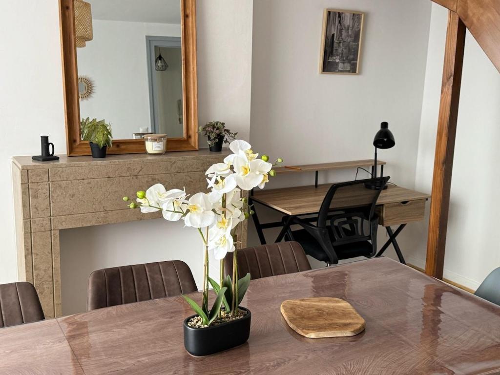une table de salle à manger avec un vase de fleurs dessus dans l'établissement Appartement l'écho des remparts, à Boulogne-sur-Mer