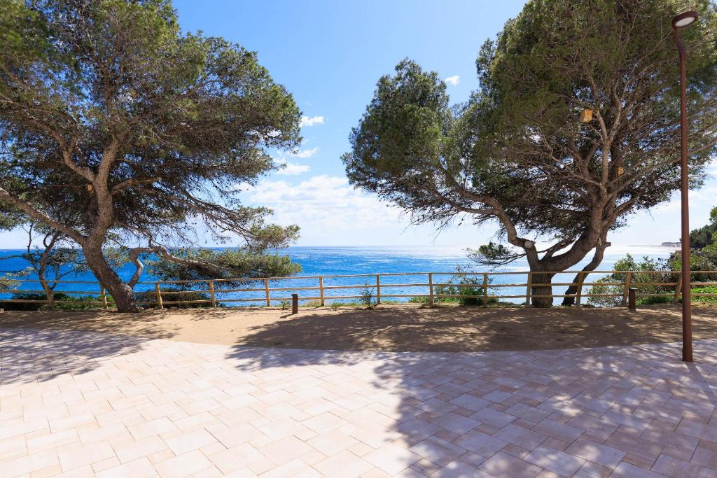 a patio with trees and the ocean in the background at Rentalmar Los Angeles in Miami Platja