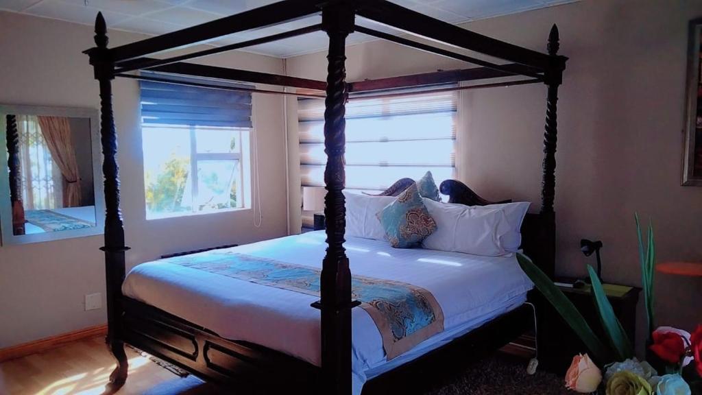 una camera con letto a baldacchino con lenzuola e cuscini bianchi di Bibby's B&B a East London