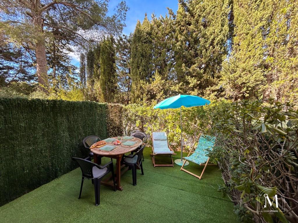une table, des chaises et un parasol sur une pelouse dans l'établissement Studio rez de jardin dans résidence avec piscine, à Bandol