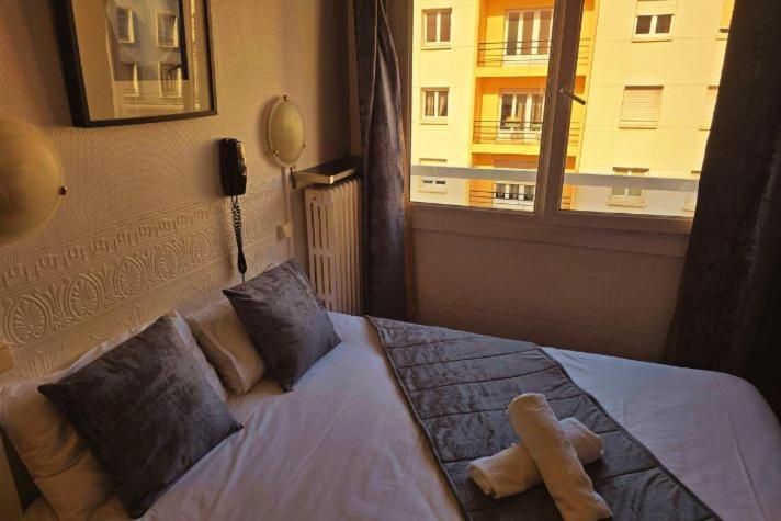 a bedroom with a bed with pillows and a window at Hôtel Alexandra Centre Ville in Boulogne-sur-Mer