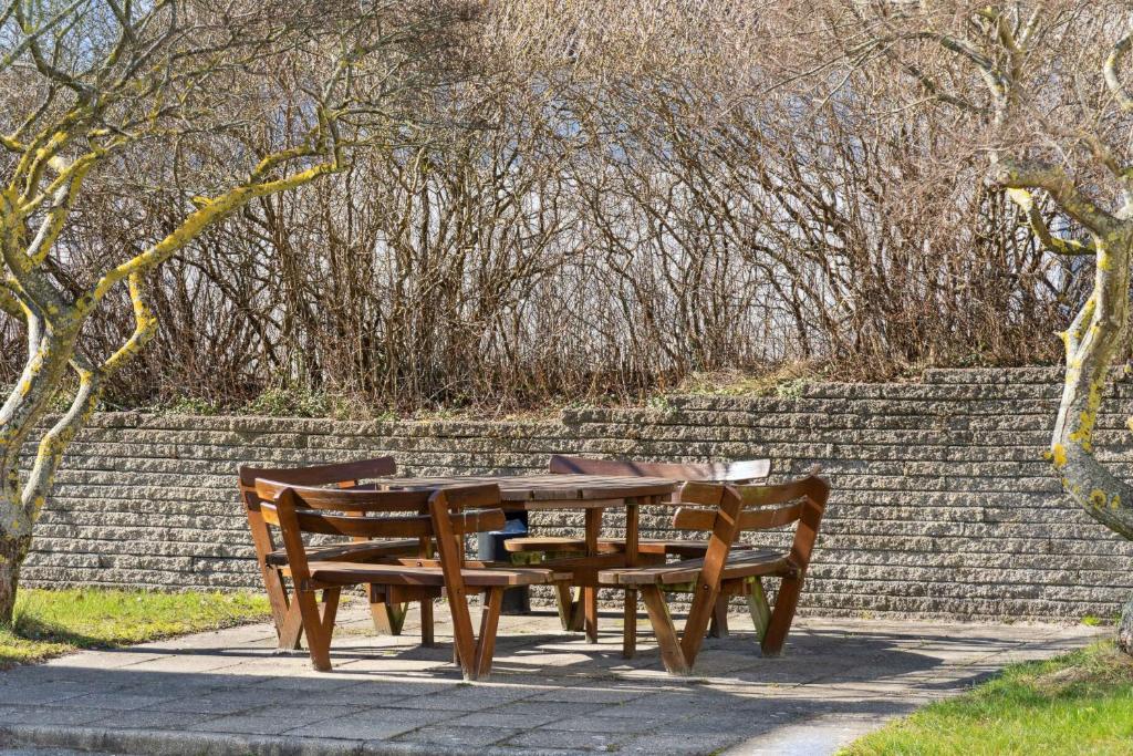 Una mesa y sillas de madera en una acera en Holiday Apartment Near Bønnerup, en Glesborg