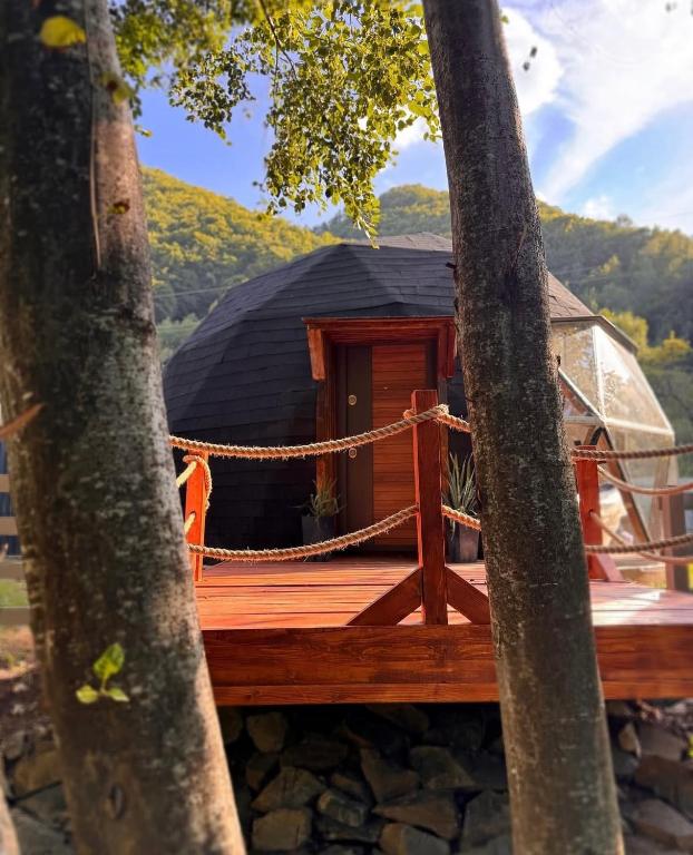 eine Holzterrasse mit Hängematte vor einem Haus in der Unterkunft Riverside Dome - Glamping Transalpina in Dobra