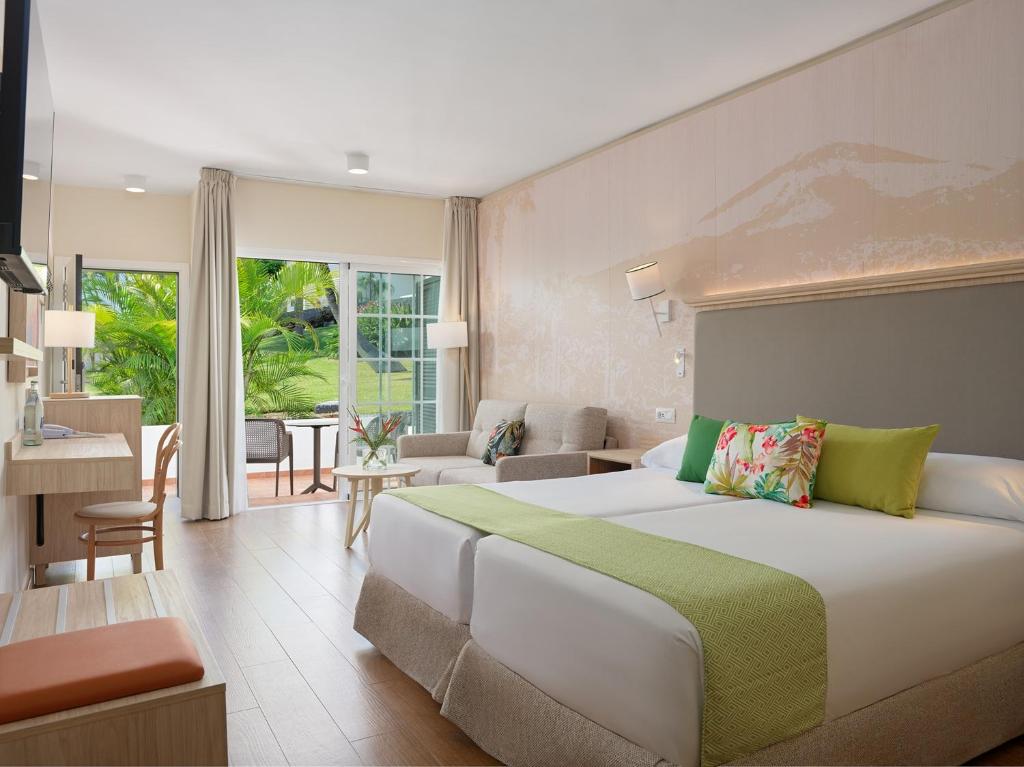 a bedroom with a large bed and a living room at Hotel Jardín Tecina in Playa de Santiago