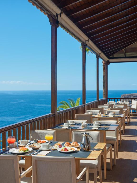 a row of tables and chairs on a balcony with the ocean at Hotel Jardín Tecina in Playa de Santiago