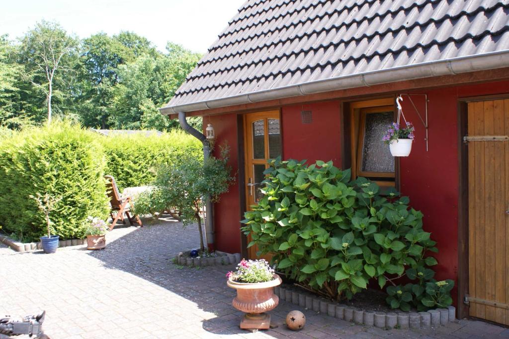 una casa roja con algunas plantas delante de ella en Dat hyggelige Ferienhus in Kappeln, en Kappeln