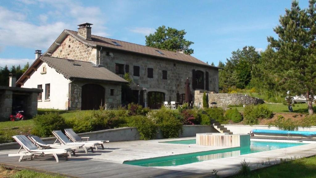 ル・シャンボン・シュル・リニョンにあるVilla spacieuse avec piscine à Le Chambon-sur-Lignonのプールとその前にラウンジチェアがある家
