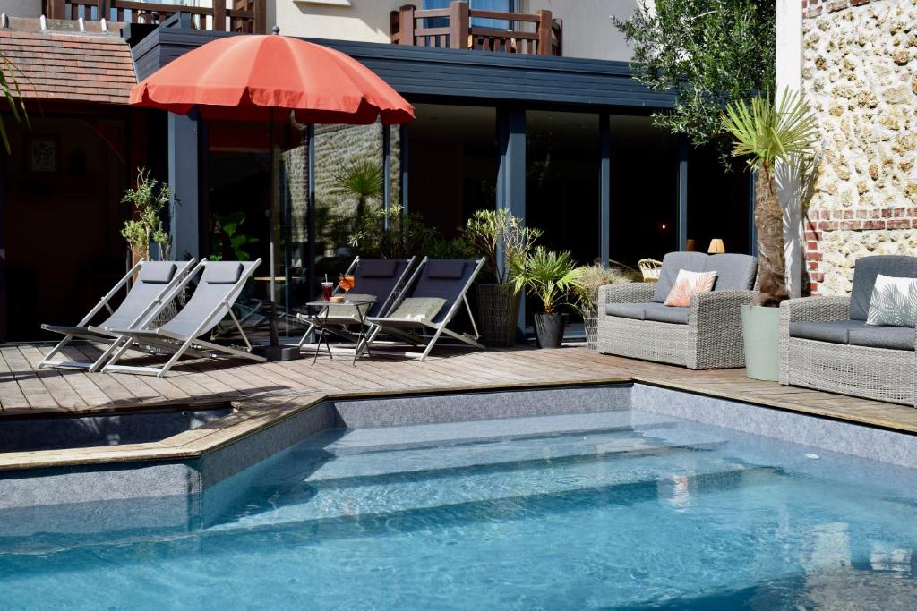a pool with chairs and an umbrella on a patio at Le Trophée Boutique Hôtel Spa- La Loggia Appart'hôtel in Deauville