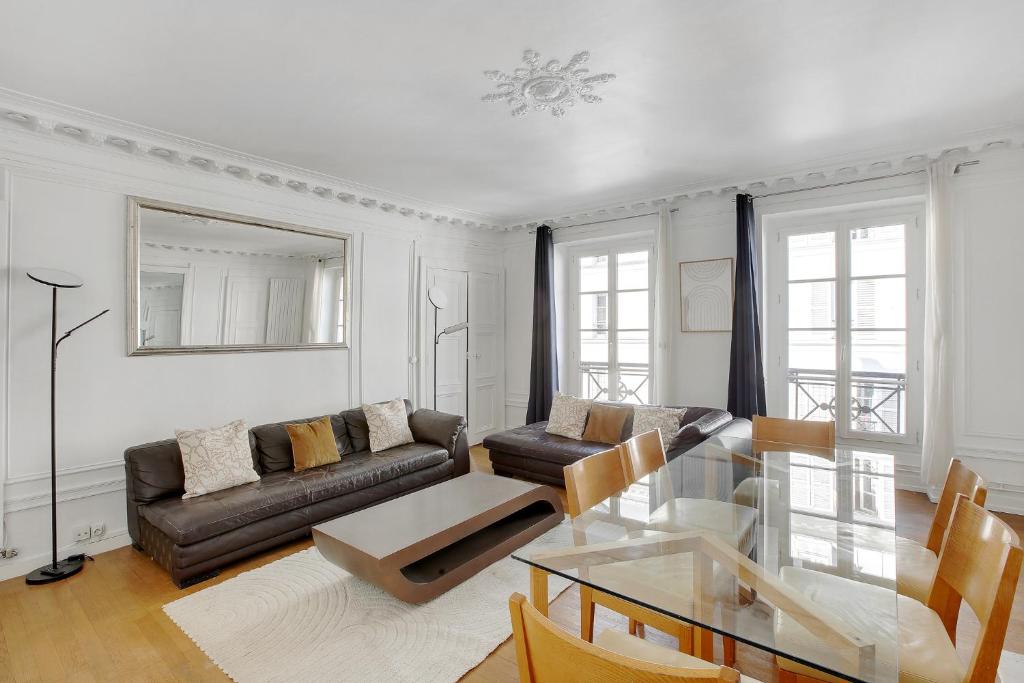 un salon avec un canapé et une table en verre dans l'établissement Élégance & confort à deux pas de la Madeleine, à Paris