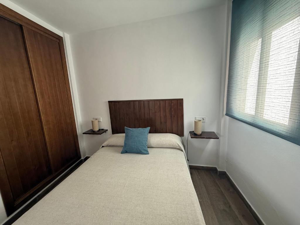 a small bedroom with a bed and a window at Apartamentos Bolonia - M a n u e l a in Bolonia