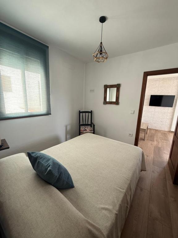 a bedroom with a bed with a blue pillow on it at Apartamentos Bolonia - M a n u e l a in Bolonia