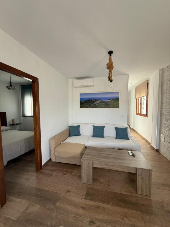 a bedroom with a bed and a couch and a table at Apartamentos Bolonia - M a n u e l a in Bolonia