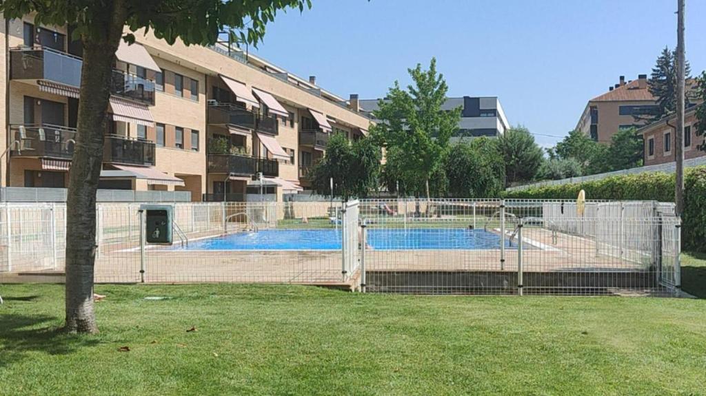 a fence around a swimming pool in front of a building at Red Wine Haro, piscina y parking in Haro