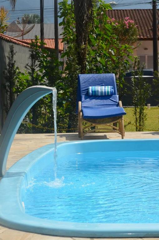 a blue chair sitting in a pool with a fountain at Casa com piscina 500m da praia condomínio Morada da Praia in Bertioga