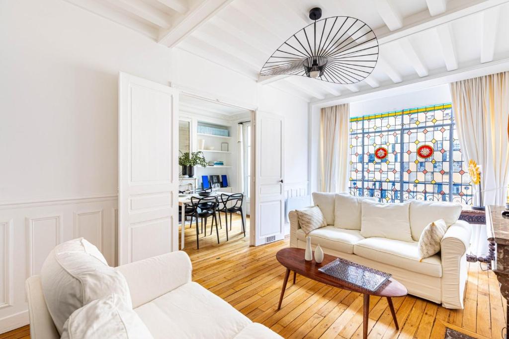 Elle comprend un salon doté d'un mobilier blanc et d'un vitrail. dans l'établissement GuestReady - Charming home in the 15th Arr., à Paris