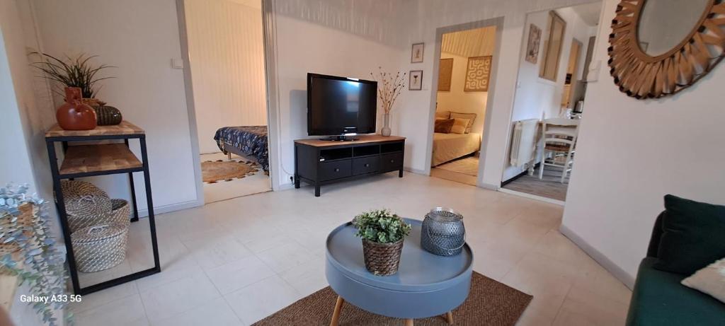 a living room with a tv and a table at Maison Calme au Centre du Village in Puisserguier